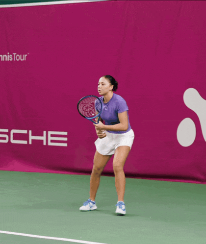 a woman is holding a tennis racquet in front of a sign that says adion helsin open
