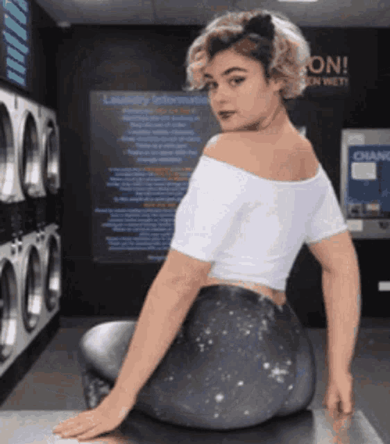 a woman sits on a counter in a laundromat with a sign that says change