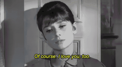 a woman is standing in front of a door and saying `` of course i love you , too . ''