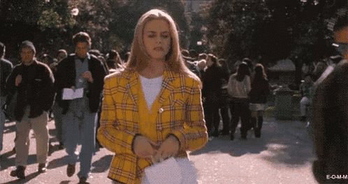 a woman in a yellow plaid jacket is walking down a street .