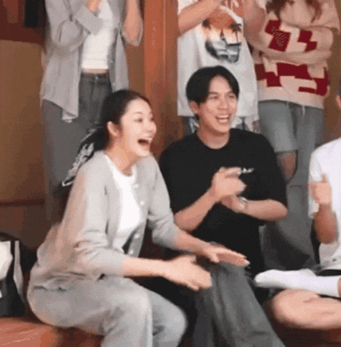 a group of people are sitting in a room laughing
