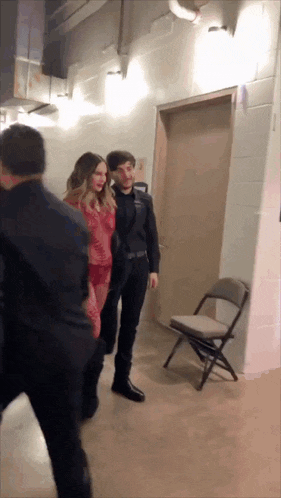 a woman in a red dress is standing next to a man in a suit