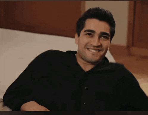 a man wearing a black shirt is smiling while laying on a bed