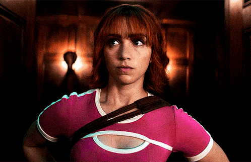 a woman with red hair is wearing a pink shirt with white stripes