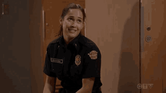 a woman in a firefighter uniform is sitting in a room next to a door .