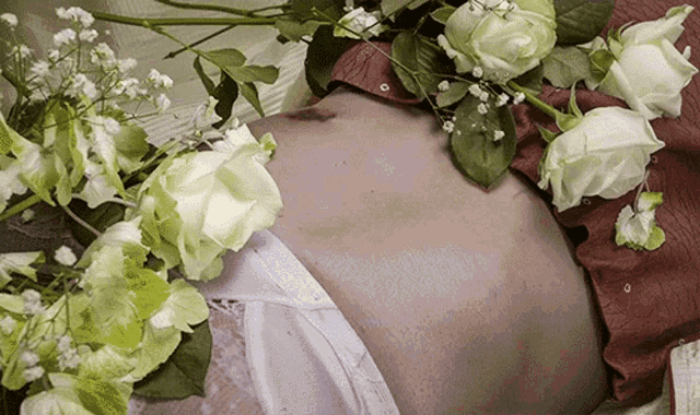 a woman laying on her stomach with white roses around her
