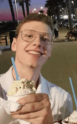 a man wearing glasses holds a bowl of ice cream
