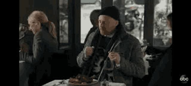 a man is sitting at a table with a plate of food and a violin .