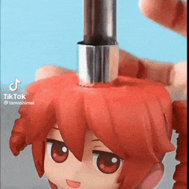 a person is holding a toy with red hair and a metal tube in their hand .