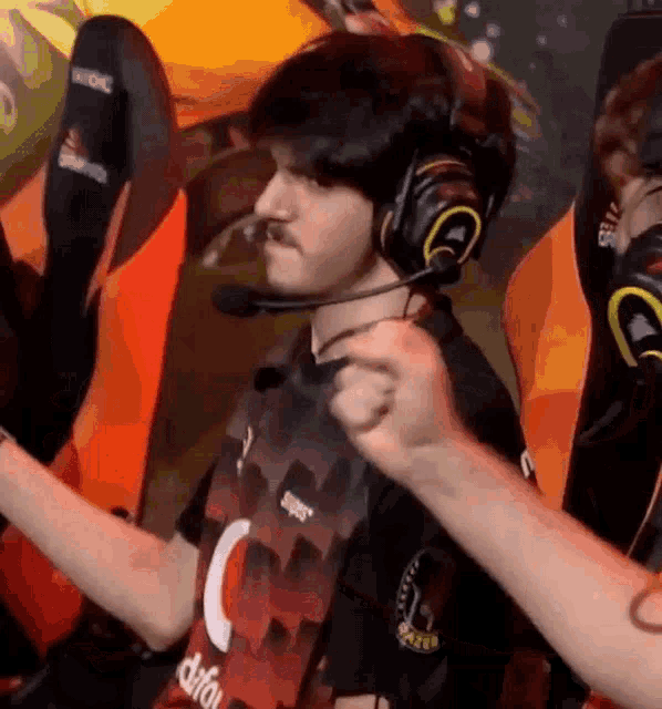 a man wearing headphones and a shirt with the letter c on it is playing a video game .