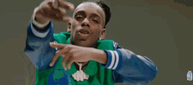 a young man in a green jacket is giving a middle finger .