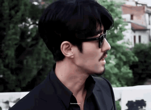 a man with a beard wearing sunglasses and a black suit