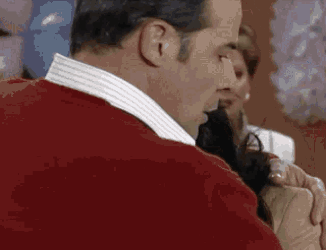 a man in a red sweater is holding a woman 's arm .