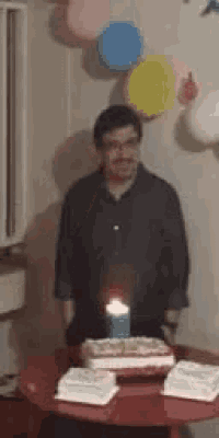 a man is standing in front of a birthday cake .