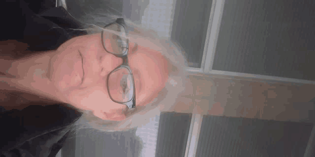 a woman wearing glasses is smiling and looking down