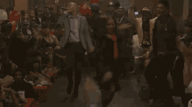 a group of people are dancing in front of a crowd at a party