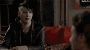 a man and a woman are sitting next to each other on a couch and looking at something .