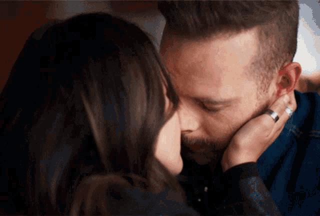 a man and a woman are kissing and the woman is wearing a silver ring