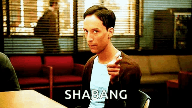 a man is sitting at a table with the word shabang written on the table