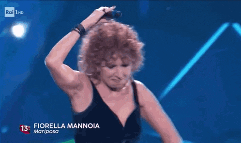 a woman singing into a microphone with the number 13 on the bottom left