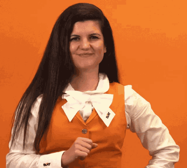 a woman wearing a white shirt and an orange vest has a button on her vest that says ' sxt '