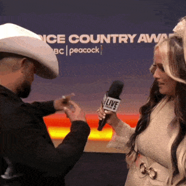 a man in a cowboy hat is being interviewed by a woman holding a microphone that says live