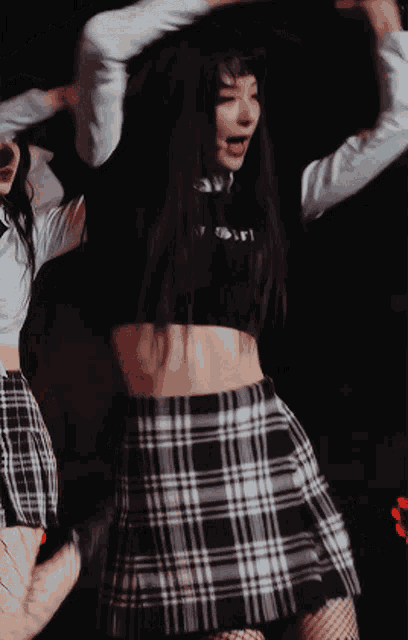 a woman wearing a plaid skirt and a crop top that says ' i 'm a girl ' on it