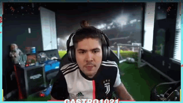 a man wearing headphones and a juventus shirt is sitting in a chair in a room .