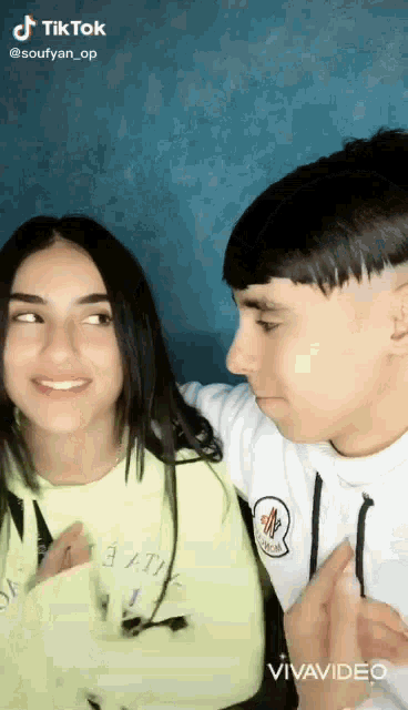 a boy and a girl are standing next to each other and looking at the camera .