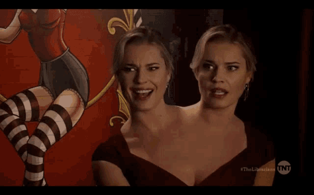 two women are standing next to each other in front of a tnt advertisement