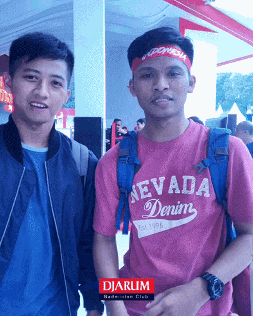 a man wearing a nevada denim t-shirt stands next to another man