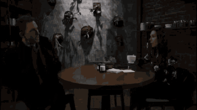 a man and a woman are sitting at a table in front of a wall with animals on it