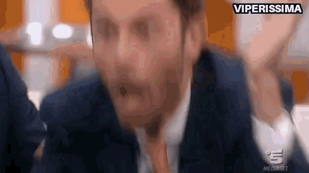 a man in a suit and tie is making a funny face in a blurry photo .