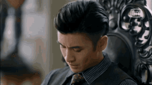 a man in a striped shirt and tie is sitting in a chair .