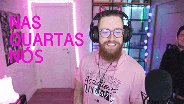a man with a beard is wearing headphones and a pink shirt with nas quartas nos written on it