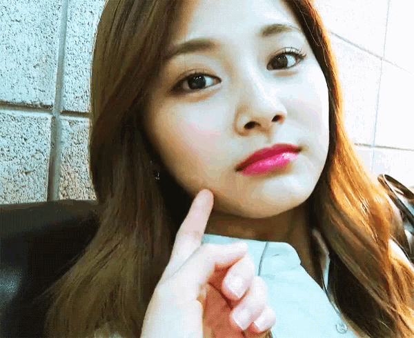 a close up of a woman 's face with her finger on her cheek