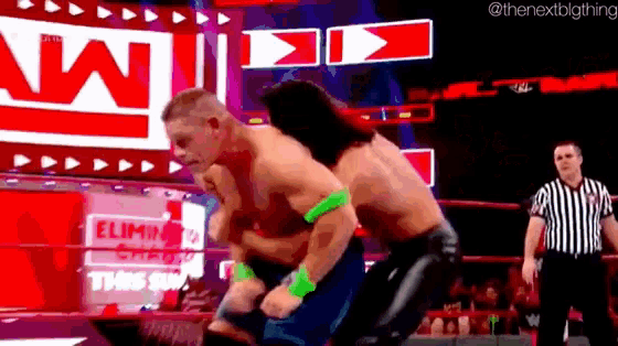 two men are wrestling in a wrestling ring while a referee looks on .