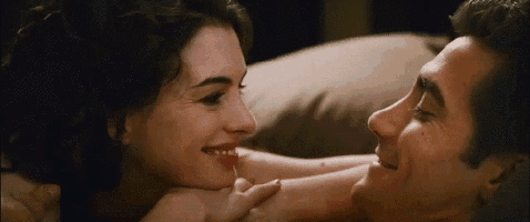 a man and a woman are laying on a bed and looking at each other