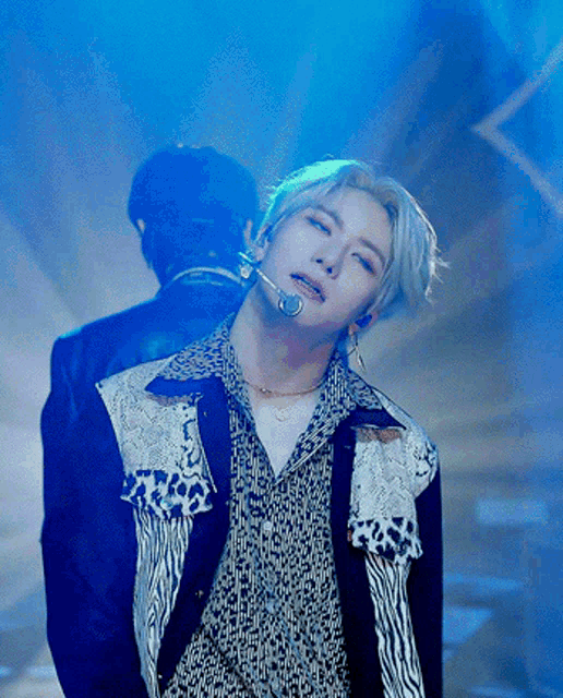 a man with a microphone in his mouth stands in front of a blue light