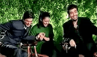 a group of people are sitting on a bench in a park laughing .