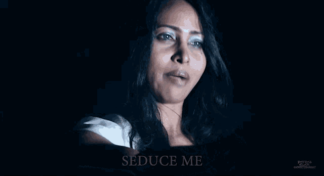 a woman in a dark room with the words seduce me written below her