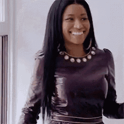 a woman with long black hair is wearing a purple leather dress and a necklace .