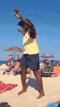 a man in a yellow tank top is dancing on a beach