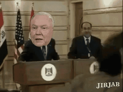 a man in a suit and tie is giving a speech at a podium with a picture of his face on it .