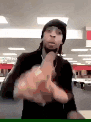 a man wearing a beanie is giving the middle finger in a room .