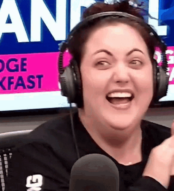 a woman wearing headphones is laughing in front of a screen that says ' lodge breakfast '