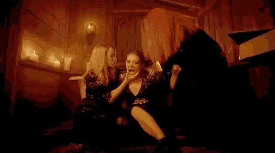 three women are sitting on the floor in a bathroom .