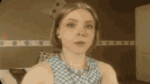 a woman is sitting on a couch wearing headphones and a checkered dress .