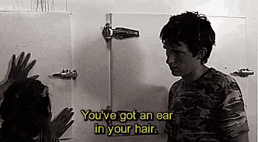 a man in a camouflage shirt is standing next to a woman in a bathroom and talking to her .