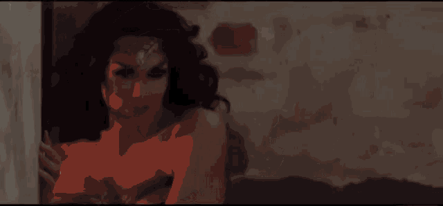 a woman in a wonder woman costume is standing in front of a wall and looking at the camera .